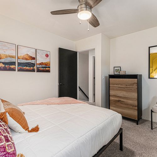 In bedroom 4, a queen-size bed is complemented by stylish decor, with an eye-catching yellow accent wall as a backdrop. The room includes a chic dresser and stylish decor.