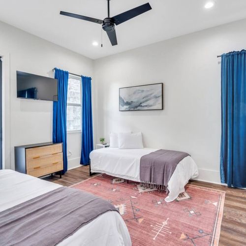 Upstairs bedroom w/ two twin beds, bold blue curtains & its own en-suite bath.