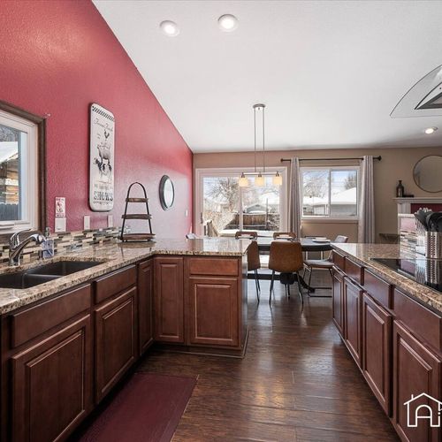 - bright kitchen with dark wood cabinets, granite counters, and a bold red accent wall
- fully equipped for meals with scenic views from the dining nook beyond
- an inviting open space that brings everyone together with warmth and style