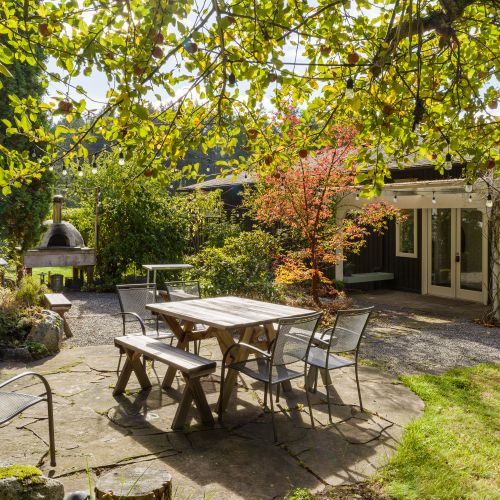 Gather under the apple trees for long meals and easy conversation. String lights, a shared table, and a wood-fired oven make this garden feel magical—perfect for pizza nights, laughter, and lingering evenings outdoors.