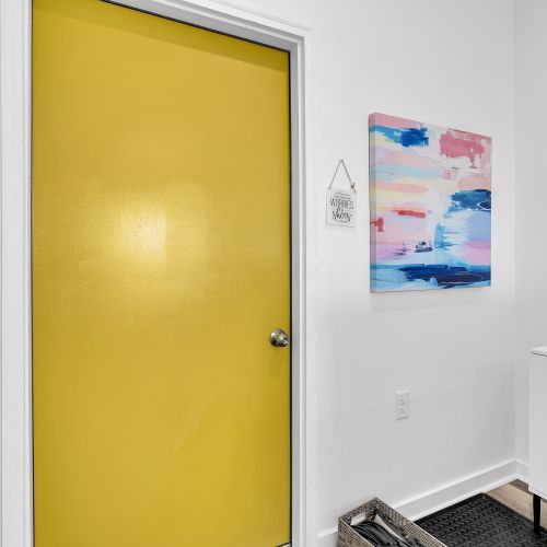 Step into a warm welcome with this bold yellow door and cheerful artwork. This colorful entryway sets a playful tone, inviting you to leave your worries (and shoes) behind and enjoy your stay!