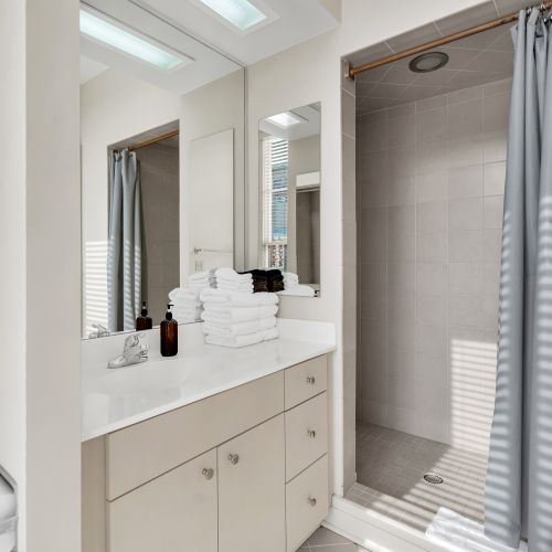 Bright, tiled bathroom w/ a clean sink vanity & mirror.