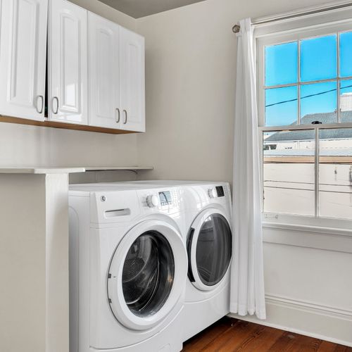 Convenient in-home laundry room with modern appliances, ample storage, and a sunlit window for added brightness.