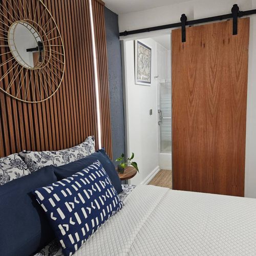 Unwind in a beautifully designed space with warm lighting from the slatted wooden headboard.