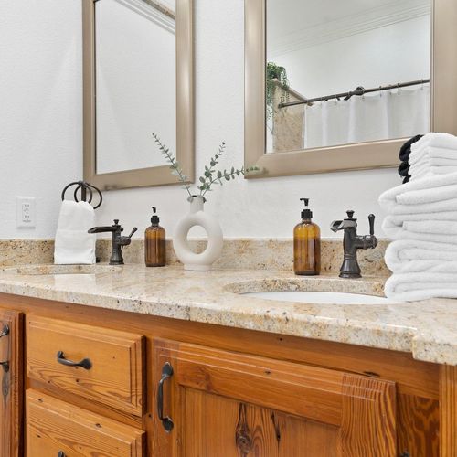 Double-sink vanity w/ marble countertop & warm wood cabinets for a spa-like feel.