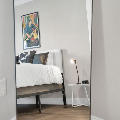 Bold artwork & a bright floor lamp give this bedroom a warm, curated vibe.