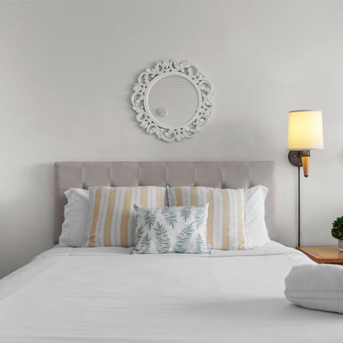 Sink into this plush, neatly made bed, featuring crisp white linens and inviting decorative pillows