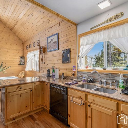 - sunlight streams through large windows highlighting rich wood textures and rustic charm
- granite countertops and dual sink make meal prep simple and scenic
- vaulted ceilings and forest views turn this kitchen into a retreat of its own