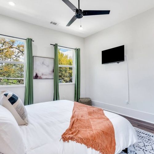 Upstairs king bedroom w/ green curtains, bright light & a relaxed, airy vibe.