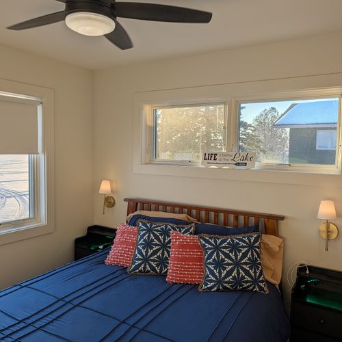 BEDROOM #1 (MAIN FLOOR):  Features a queen-size bed, ceiling fan, nightstands, nightlamps, dresser, mirror, private television, closet, and a great view of Crystal Lake!