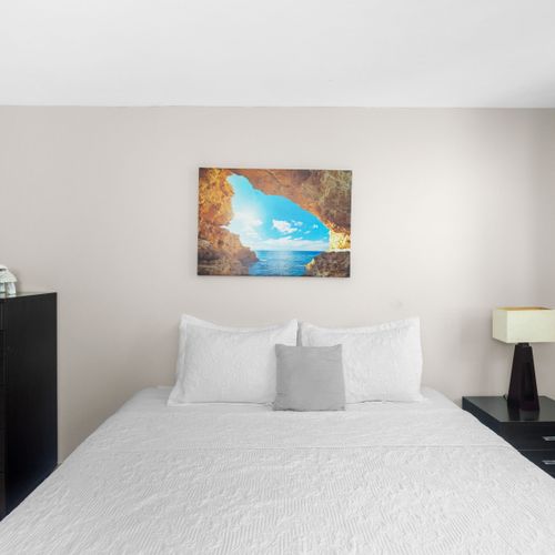 A cozy queen bed with pristine linens and vibrant artwork, creating a peaceful retreat for your tropical getaway.