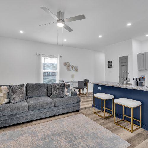 Enjoy this stylish and spacious open-concept living area, complete with a plush sofa, vibrant accents, and a fully equipped kitchen with a breakfast bar. Perfect for relaxing, entertaining, or sharing meals in a comfortable, inviting space.