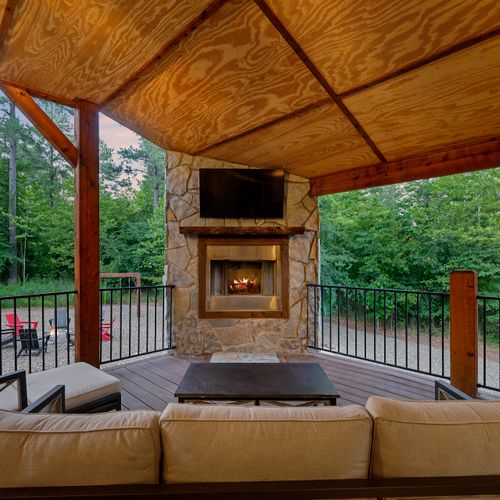The covered outdoor patio on the main level. Outdoor seating around a fireplace.