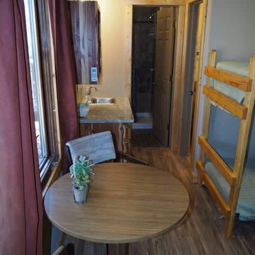 Main room:  features a small dining table with chairs, kitchenette  / sink, one twin-on-full bunk bed, and one twin-on-twin bunk bed.