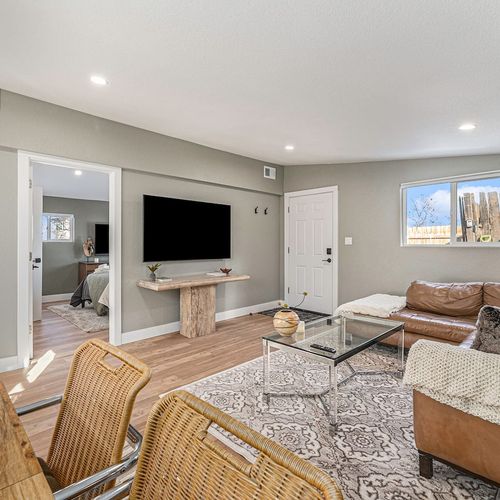 - light filled living room with mounted smart tv, entry access, and leather sectional seating
- woven dining chairs and soft rugs give texture and warmth to the design
- ideal for downtime, with easy flow into bedrooms and main hallway