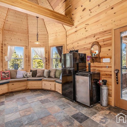 - unique turret style nook with wraparound bench seating and towering windows
- includes a compact bar area with dual refrigerators and plenty of natural light
- perfect for reading, sipping, or catching up with friends in cabin comfort