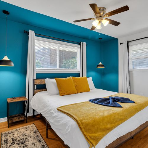 Rest easy in this stylish bedroom featuring a plush king-sized bed and bold NOLA-inspired colors. The perfect blend of comfort and flair awaits your stay!