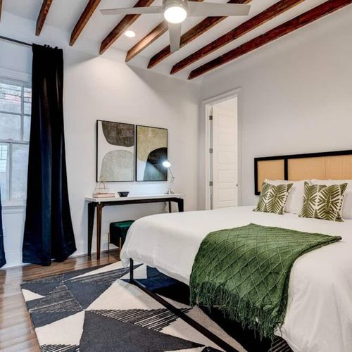 Serene master bedroom w/ a lush green bed & ensuite bath — your private retreat.