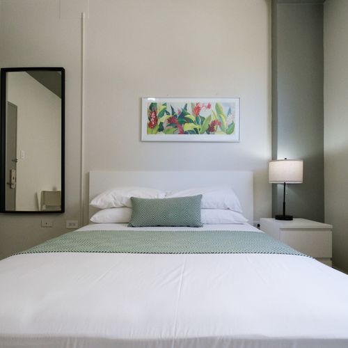 Drift into a peaceful slumber in our beautifully appointed bedroom featuring a plush queen-sized bed, crisp linens, and soft lighting for ultimate relaxation after a day of exploring.