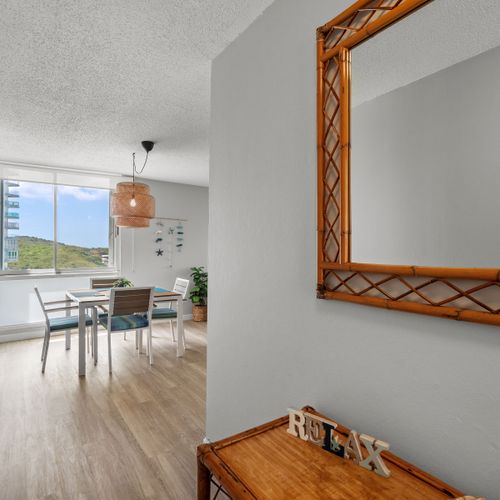 "Panoramic living experience! This inviting perspective captures the expansive living and dining areas, seamlessly leading your eye towards the bright balcony and the beautiful outdoor views beyond