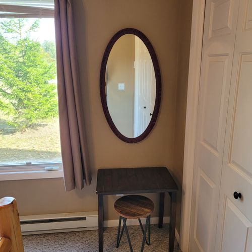 BEDROOM #1 (FIRST FLOOR):  Features a beautiful queen-size bed, ceiling fan, dresser, nightstand, lamp, closet, and makeup table with chair and mirror.