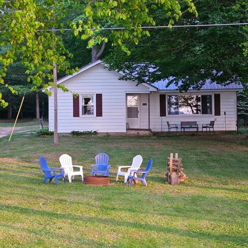 Overall:  the front of the cabin in summer with the private bonfire ring in the front yard.