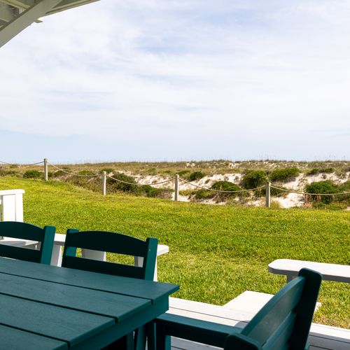 Grassy yard with cozy chairs captures sea breeze and barefoot walkways to shore.