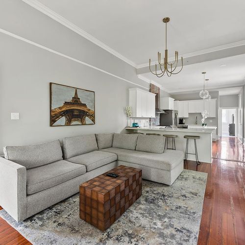 Bright and open living area with a stylish sectional and sleek kitchen, perfect for relaxing and entertaining.