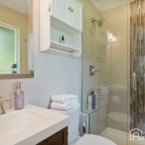 Relax and rejuvenate in the shared bathroom, featuring a walk-in glass door shower and all the basic amenities you need.