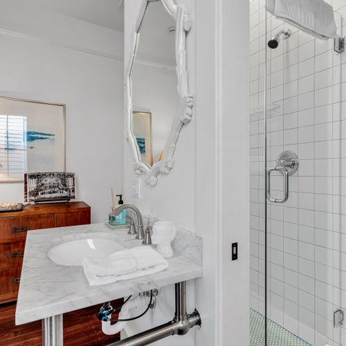 Bright, clean bathroom w/ a glass-enclosed shower.