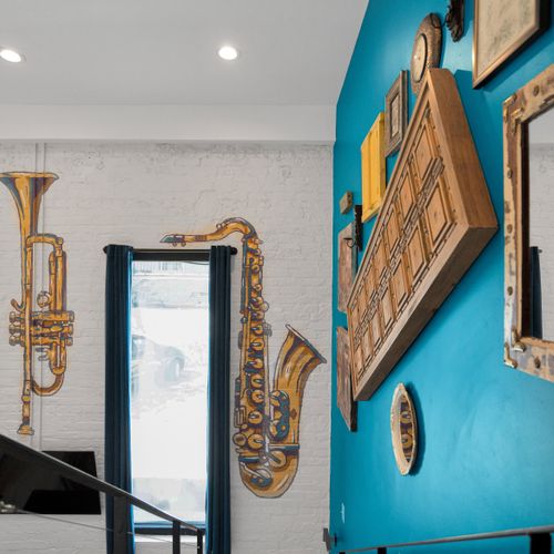 Trumpet & ornate framed art on a teal wall celebrate the city's rich musical heritage.