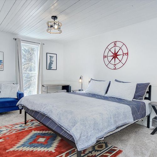 - spacious bedroom with king bed, plush bedding, and calming blue and white palette
- coastal charm with compass wall art, cozy navy loveseat, and southwest style rug
- desk nook and abundant natural light make it great for work or relaxation