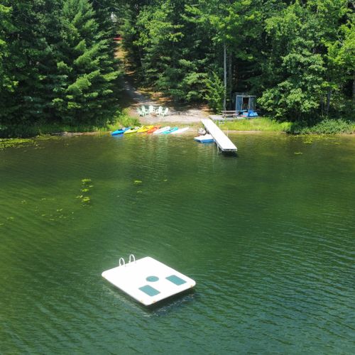 Exterior:  an aerial view of the private lakefront with the private swim raft in the forefront.