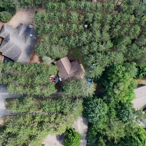 EXTERIOR:  A broader aerial view, showing the end of the cul-de-sac on which the cabin is located.