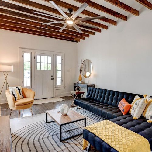 Bright living room w/ exposed brick, bold blue sofa & warm wood accents — made for gathering.