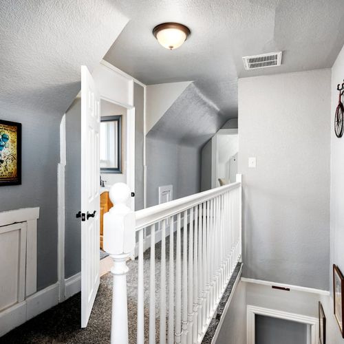 - hallway features sloped ceilings, cozy carpeting, and a bright open layout
- multiple nooks and doorways give access to private upstairs guest rooms
- natural light and simple decor make this a serene connecting space