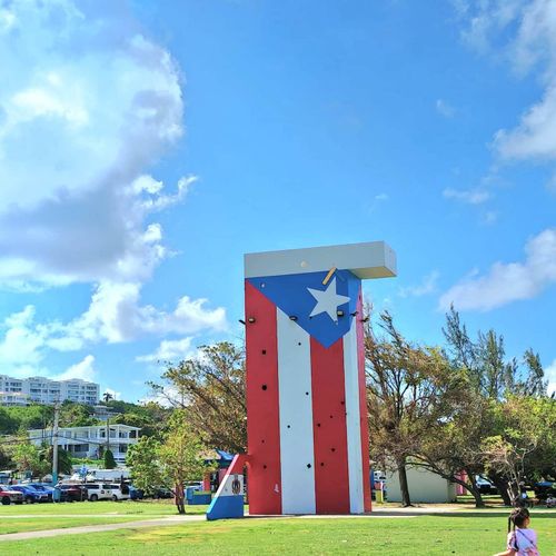Iconic Puerto Rico flag monument standing tall under a beautiful blue sky. A vibrant landmark for your visit!