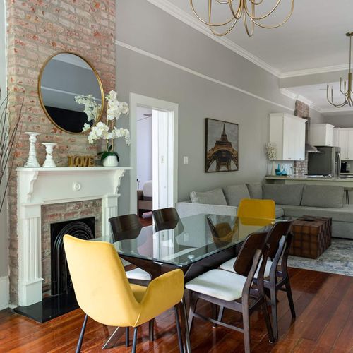 Charming dining space with exposed brick, chic chandelier, and a cozy fireplace setting the perfect ambiance for meals or gatherings.