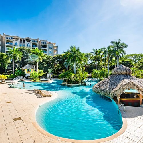 The large pool near the condos with lots of trees, and the pool bar