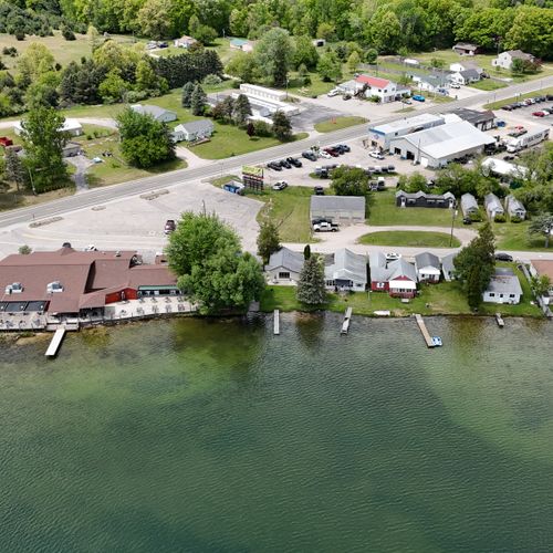 Exterior:  a  high up front drone shot of the house with the lake in the front and the turk lake restaurant and bar just to the left of it.