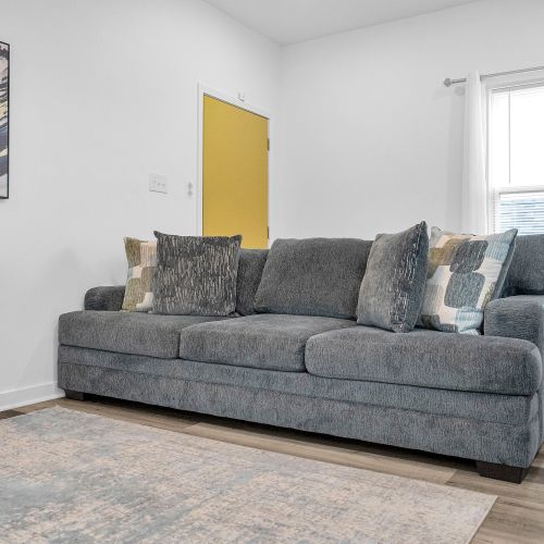 Relax in style on this plush, inviting sofa that anchors the living area with comfort and charm. Paired with modern decor and a pop of color from the yellow door, it’s the perfect spot to unwind after exploring the city.