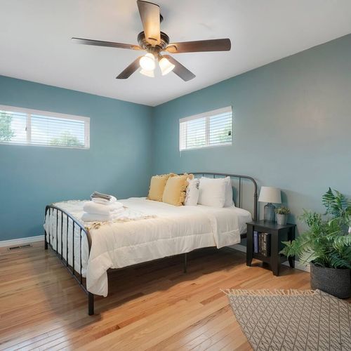 - serene bedroom with calming blue walls, cozy linens, and natural light from two windows
- ceiling fan overhead and leafy greenery add both style and comfort
- perfect for unwinding after a long day or enjoying a lazy morning in bed