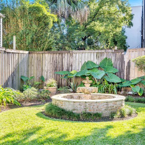 Beautiful backyard oasis featuring a charming stone fountain surrounded by lush greenery, perfect for relaxation.