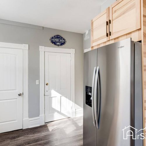 - sleek stainless steel fridge with upper cabinets for extra storage and organization
- back door provides easy access for unloading groceries or stepping out
- wood floors and farmhouse style trim tie the space together beautifully