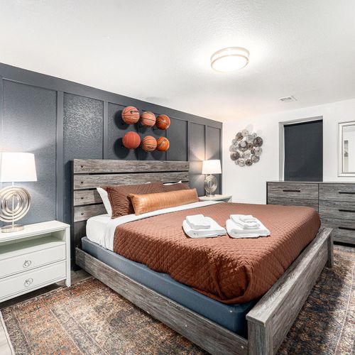 Sporty vibes define this downstairs king bedroom, adorned with basketball accents on the walls for a playful and comfortable retreat.