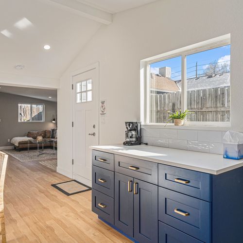 - brew your morning coffee while the sunshine pours in through large windows
- bold navy cabinets with brass handles add style and functionality to the space
- welcoming corner with peaceful outdoor views and room to prep or unwind