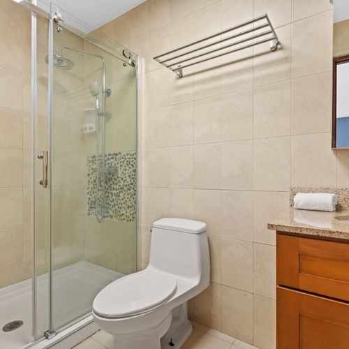 Start your day fresh in this clean bathroom. The modern fixtures and warm wooden vanity create a relaxing and stylish space.
