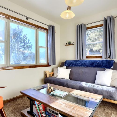 - cozy futon and warm wood tones make this living space extra inviting
- large windows let in tons of natural light and offer peaceful tree filled views
- enjoy a shelf full of classic board games for fun, relaxing nights indoors