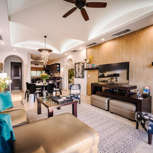 Combined living and dining room with leather sectional, coffee-table chess set, dining table for six, chandelier, and archway to kitchen.