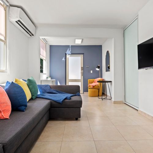 Relax in a modern living space. Our cozy sofa with colorful pillows offers the perfect spot to unwind and enjoy a comfortable stay.